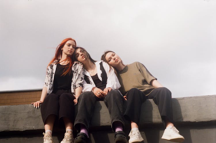 Three Girls Sitting Together On Wall