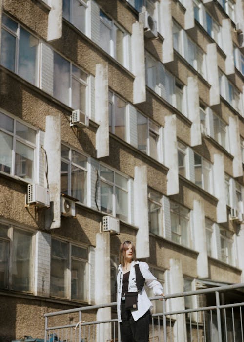 Woman Standing by the metal Fence Near Concrete Building