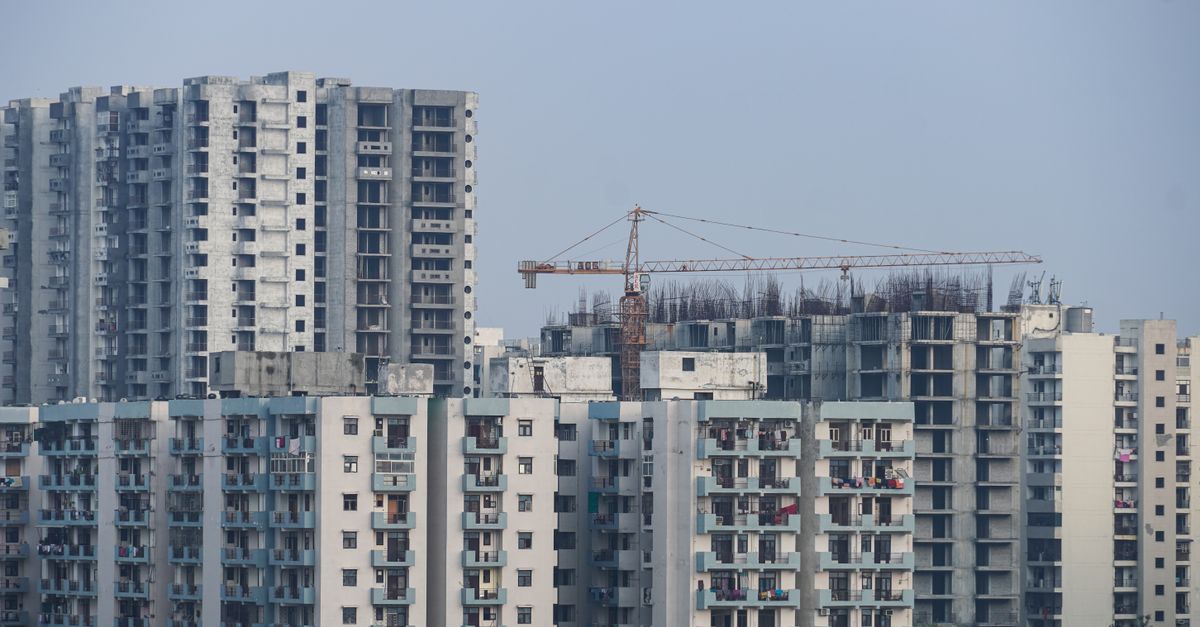 Modern high-rise buildings under construction with cranes in a cityscape.