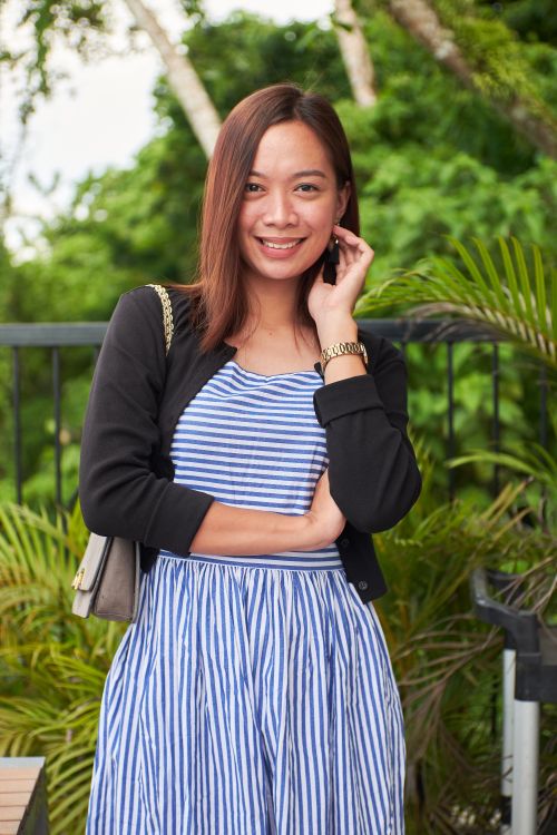 Free Portrait of a smiling woman in a striped dress standing outdoors on a sunny day. Stock Photo