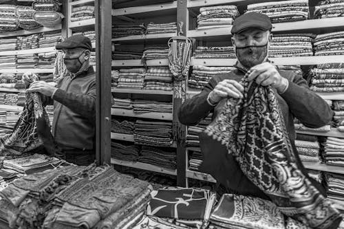 Grayscale Photo of Man Folding A Fabric