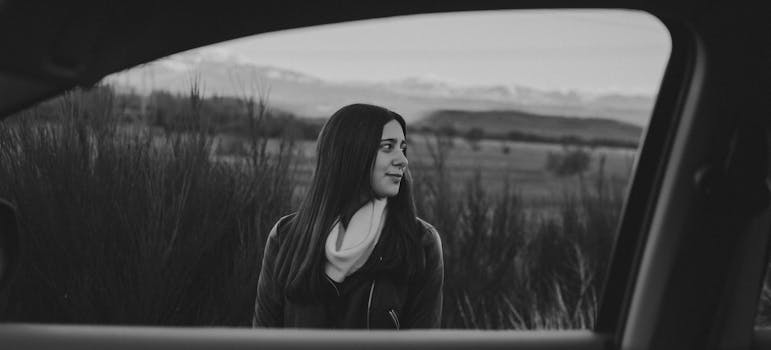 Monochrome portrait of a woman looking sideways through a car window.