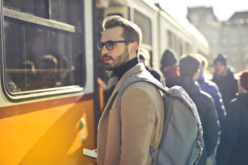 Free Man in Brown Coat and Gray Backpack Posing for a Photo Stock Photo