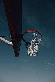 Low angle shot of a basketball hoop and net with a dramatic sky backdrop, ideal for sports themes.