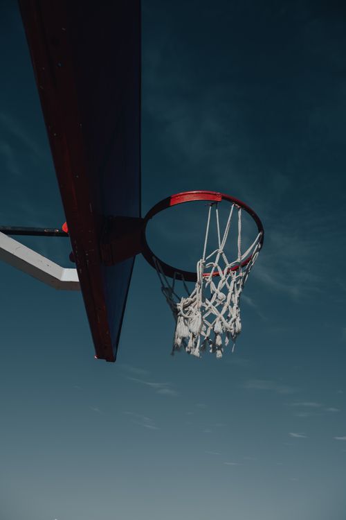 Free Low angle shot of a basketball hoop and net with a dramatic sky backdrop, ideal for sports themes. Stock Photo