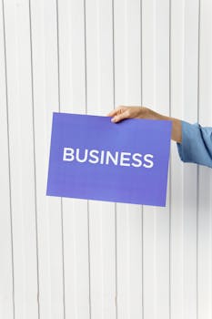A hand holds a blue placard with 'Business' signage against a white background, ideal for startup themes.