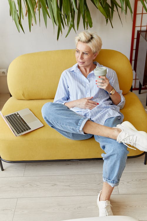 An Elderly Woman Sitting on a Couch while in Deep Thought