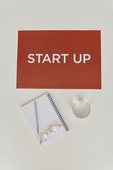 Inspiring minimalistic startup concept with notebook, pen, glasses, and glass of water.