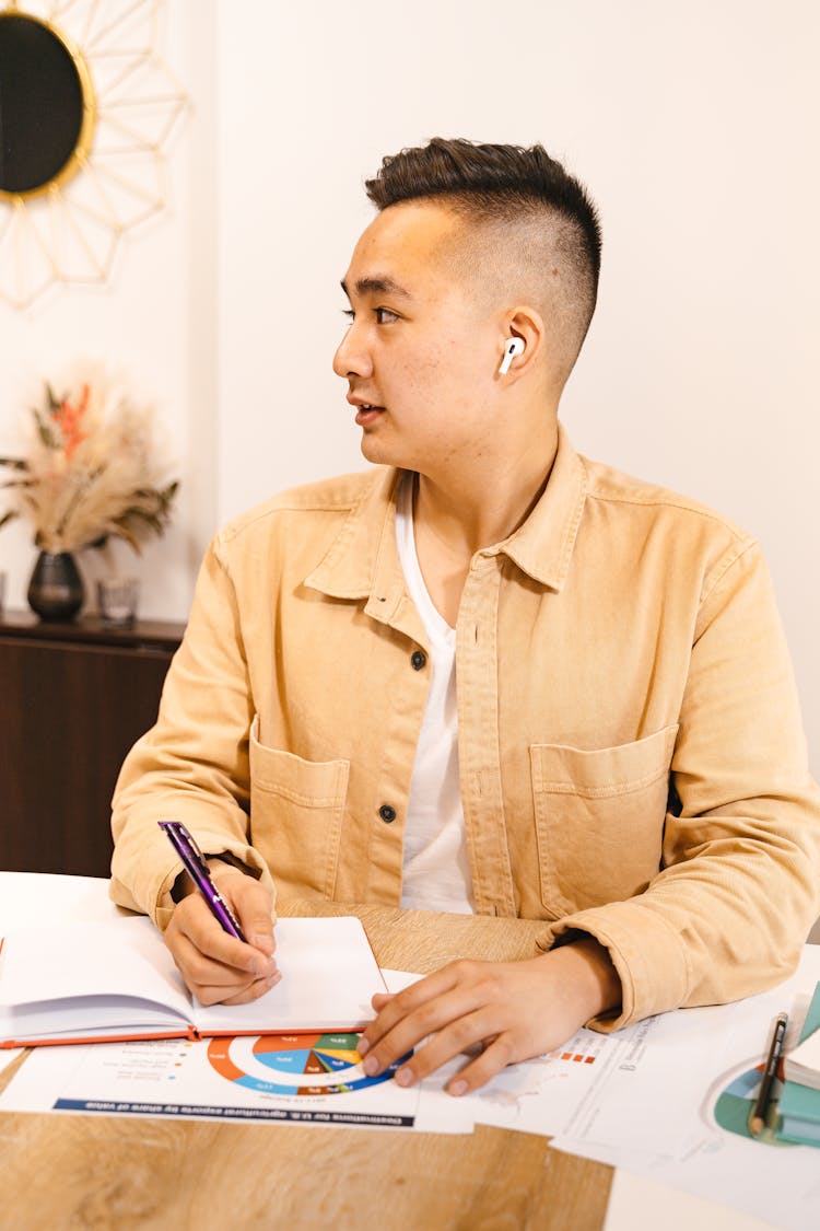 A Man In Brown Unbutton Long Sleeves Shirt Holding A Pen