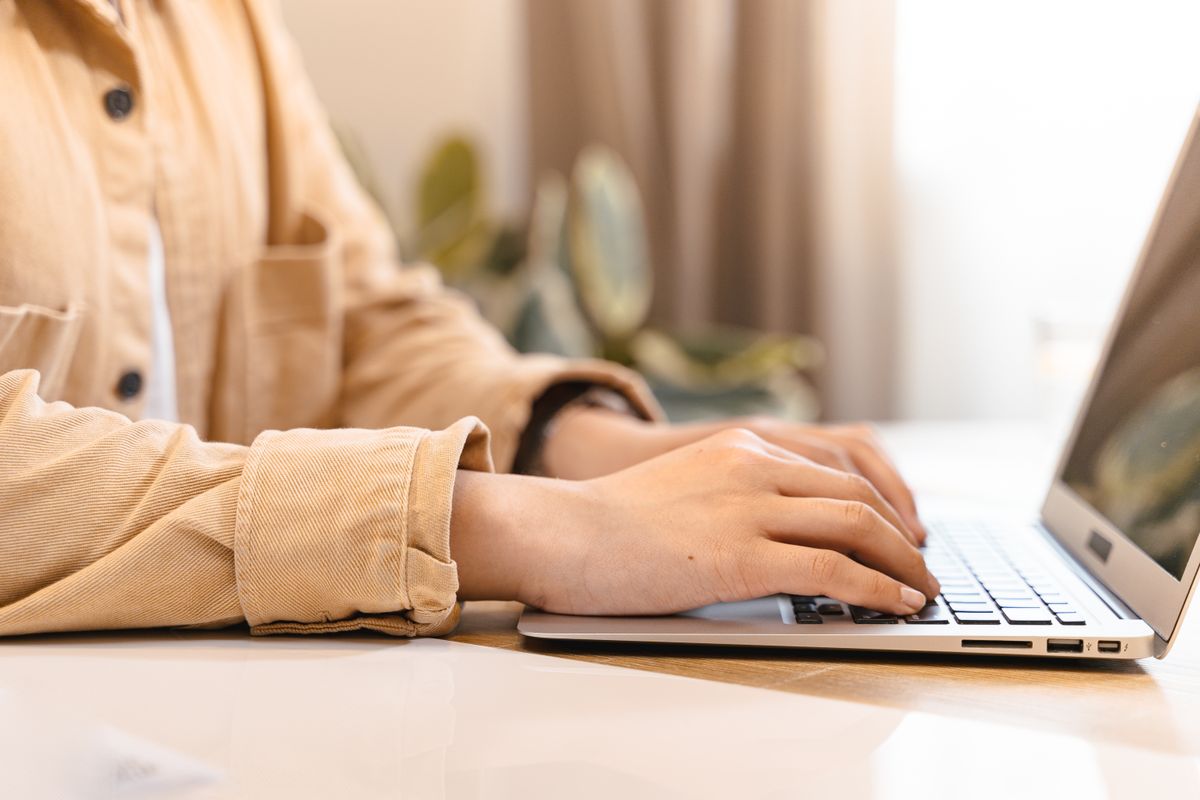 Hands typing on a laptop keyboard indoors