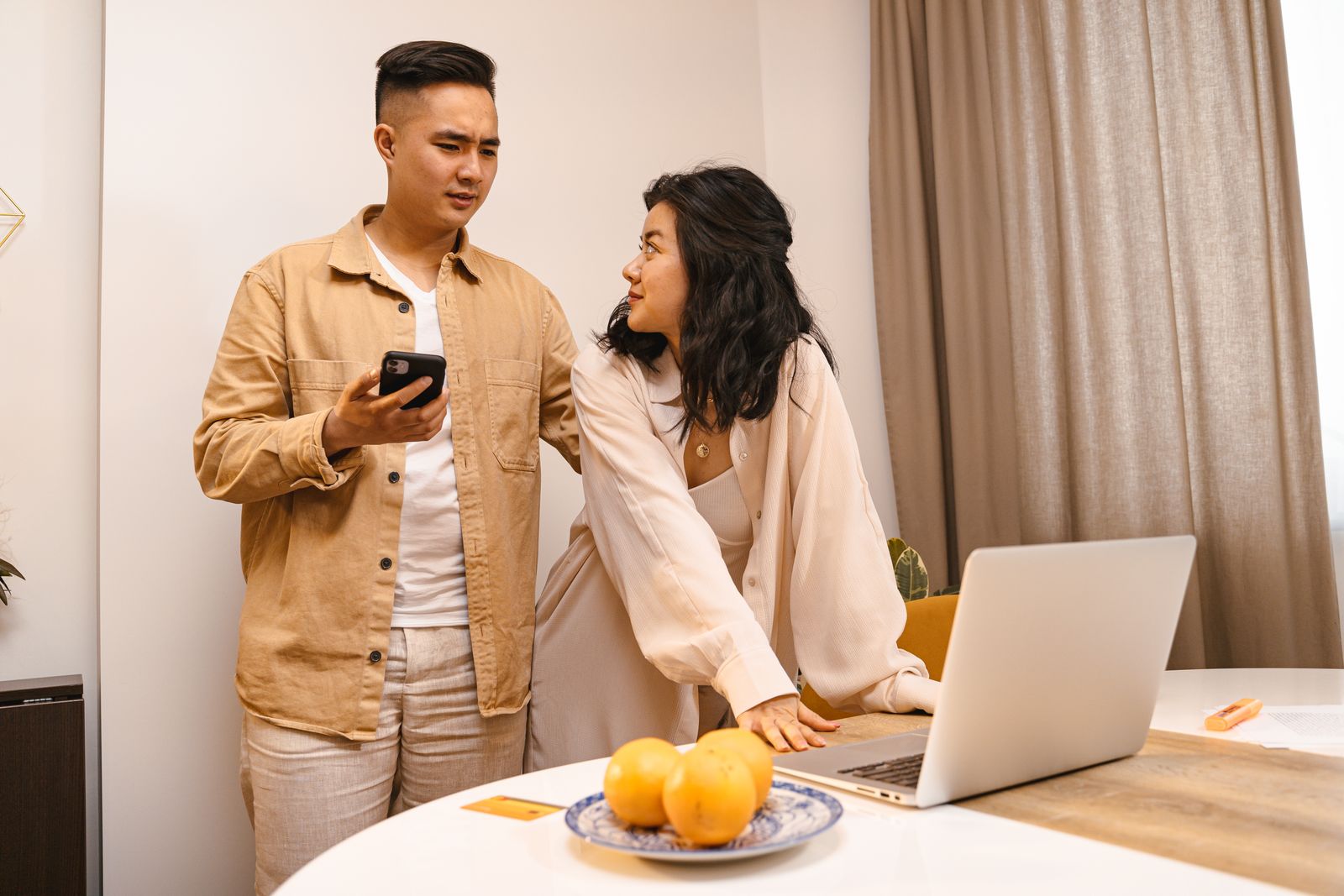 Two people looking at a laptop and smartphone at home