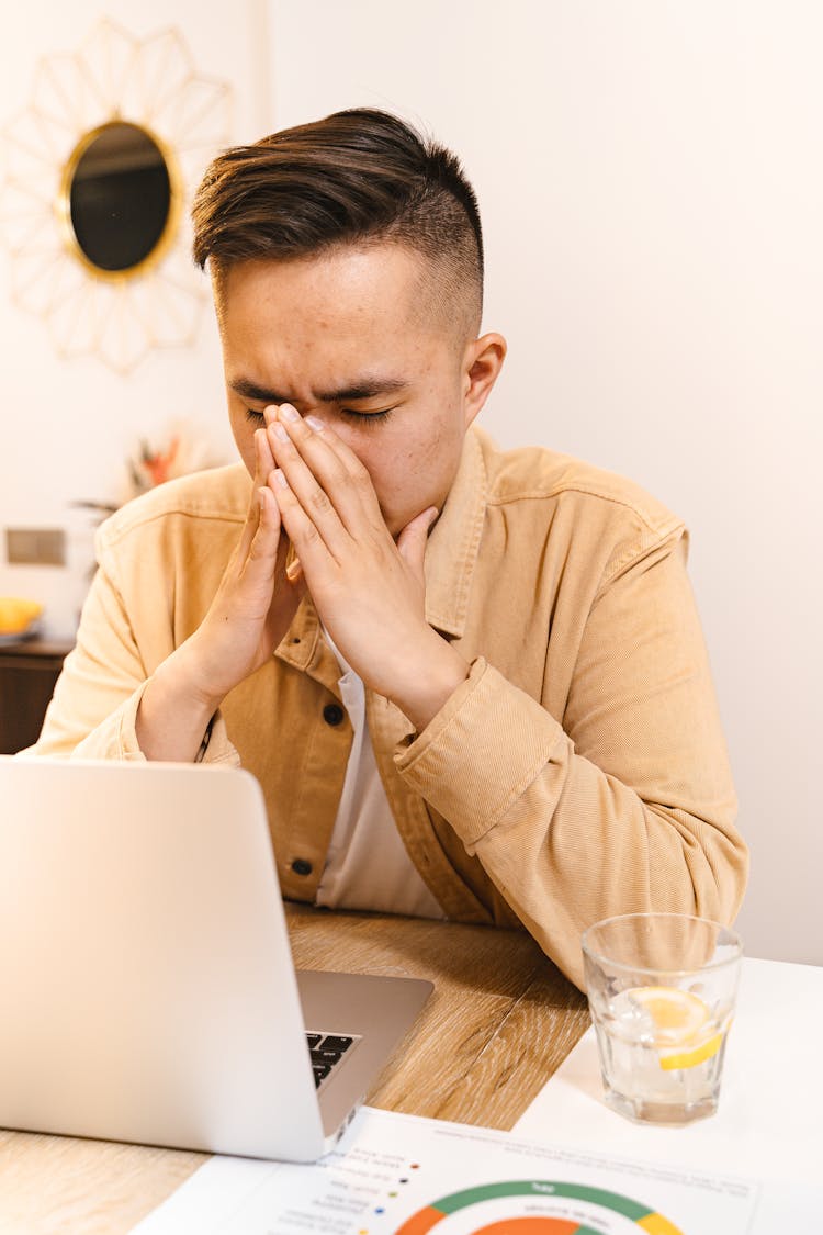 Man In Brown Jacket Concentrating In Front Of A Laptop



