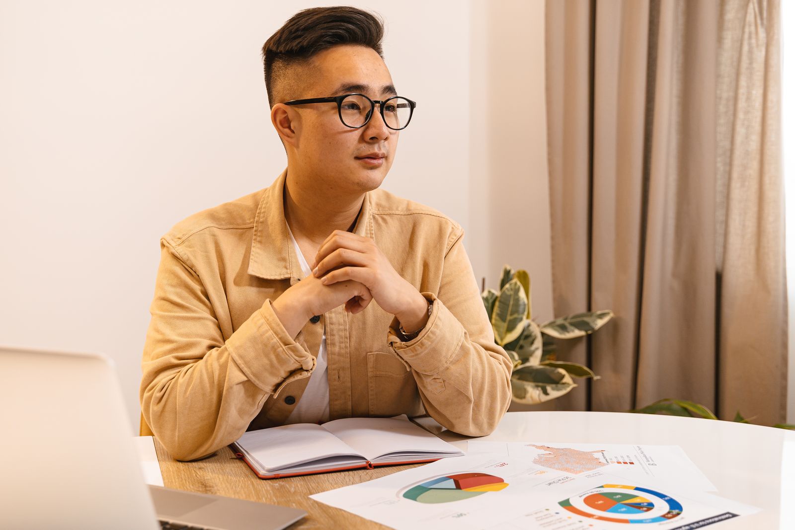 A businessman reviews compliance documents spread across a table in his office.
