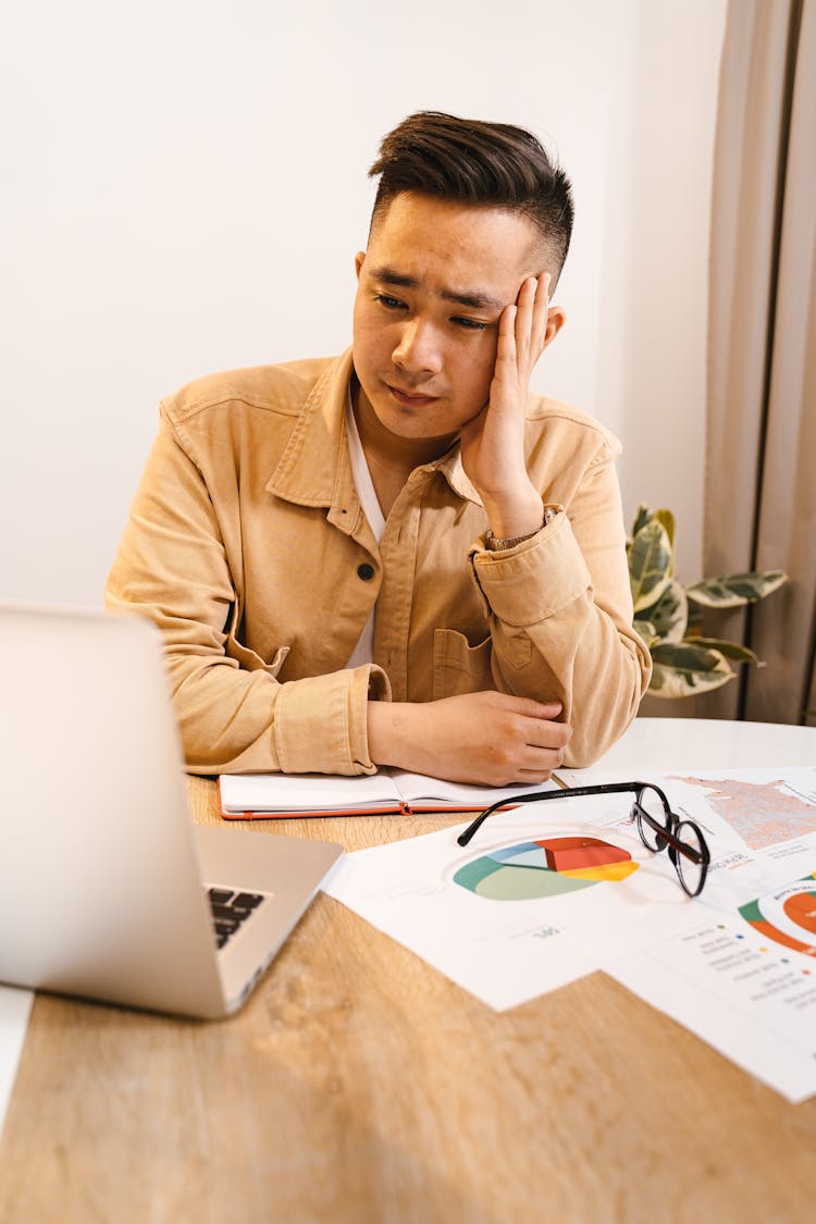 Frustrated Man Sitting By Laptop At Work