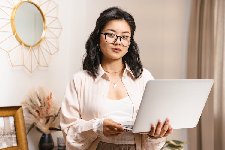 Woman In Eyeglasses Standing In Room With Open Laptop