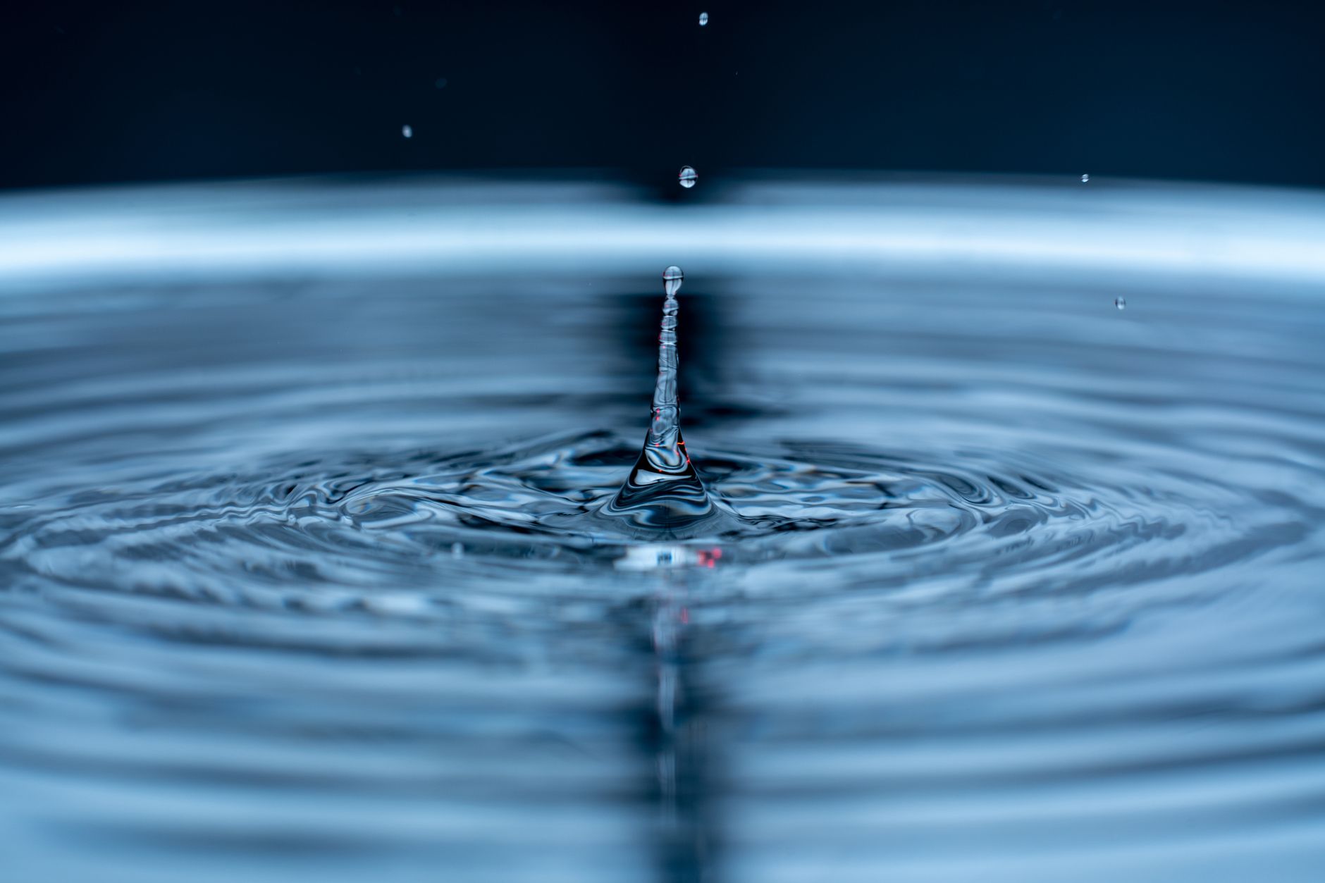 Detailed shot of a water droplet causing ripples, showcasing liquid dynamics.