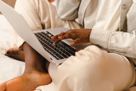 Person uses laptop while sitting comfortably indoors, showcasing modern technology in a relaxed environment.
