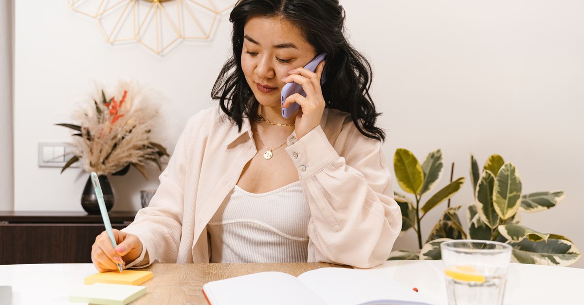 person on phone call at home taking notes