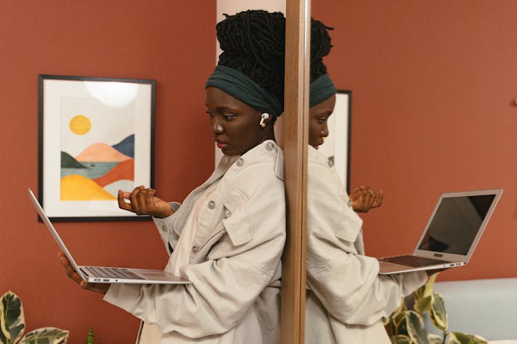 Woman Standing By Mirror With Open Laptop