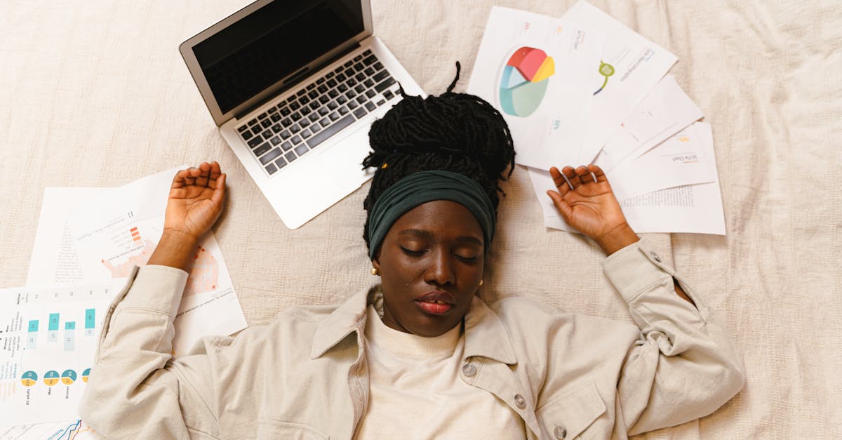 Tired woman with closed eyes lying by laptop and papers after work.
