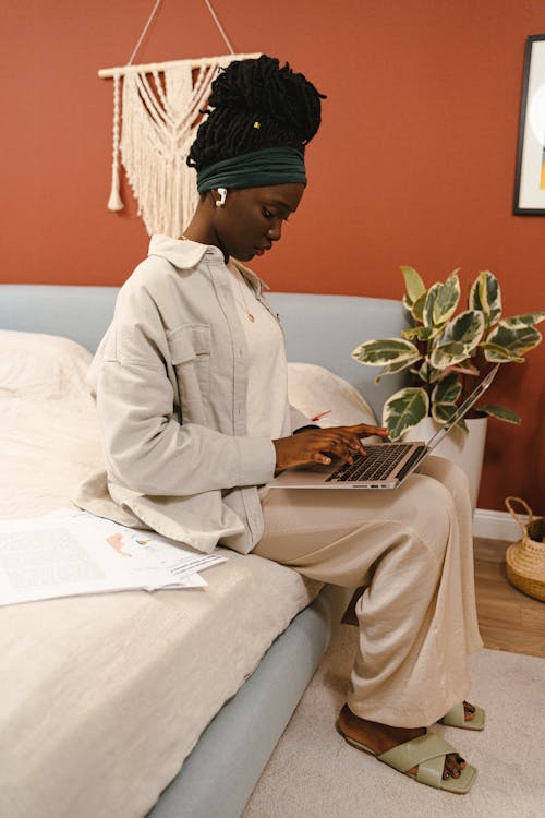 A Woman Sitting on the Bed while Using Her Laptop