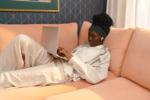 Woman in White Button Up Shirt Sitting on Couch Using Silver Laptop