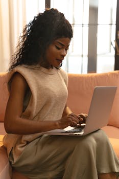 Young woman working on laptop indoors, highlighting technology and modern lifestyle.