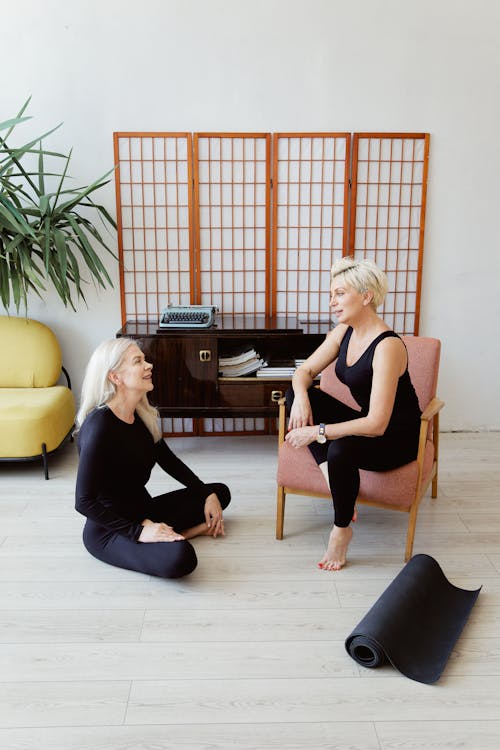 Woman Sitting on the Floor While Having a Conversation with Another Woman