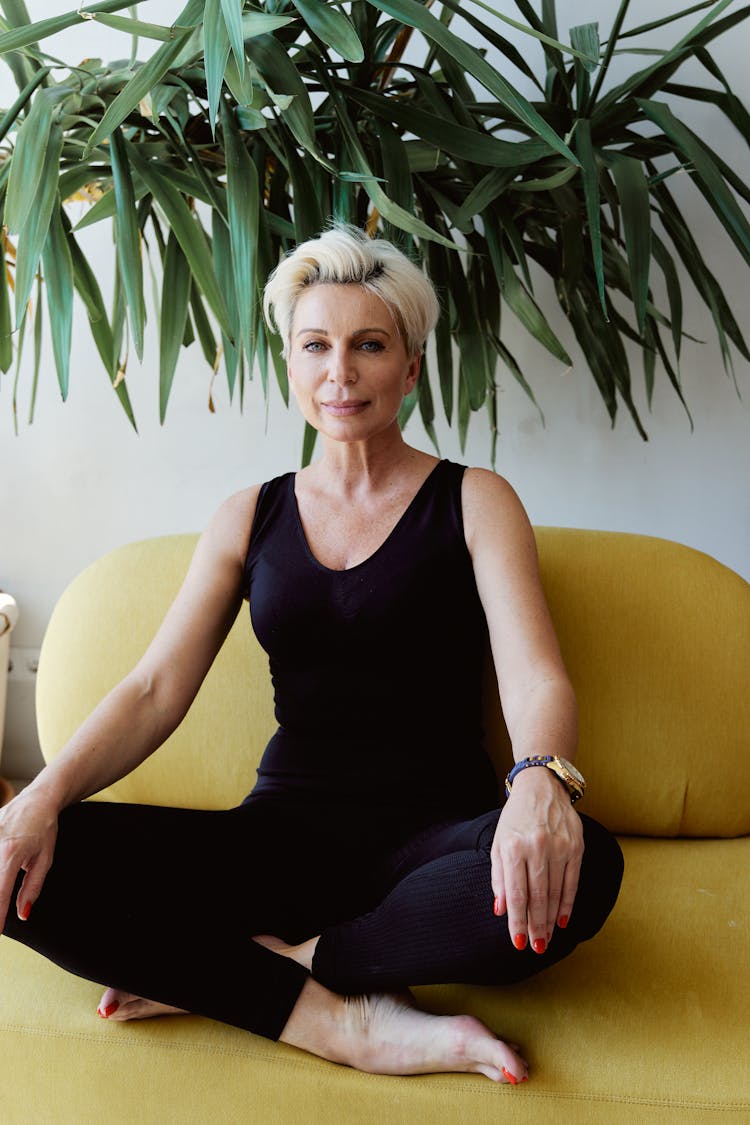 Woman In Black Tank Top And Leggings Sitting On A Yellow Couch 