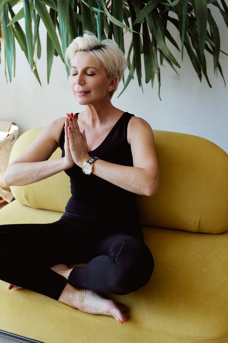 Close-Up Shot Of A Woman Meditating While Sitting On A Couch