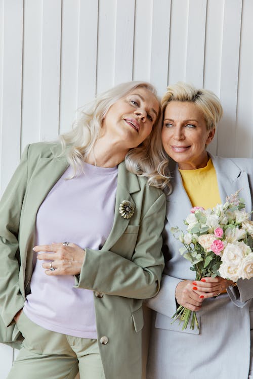 
A Woman in a Blazer beside another Woman Holding a Bouquet of Flowers