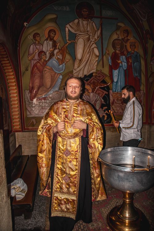 Free Orthodox priest wearing a detailed cassock in a church setting, with religious icons. Stock Photo