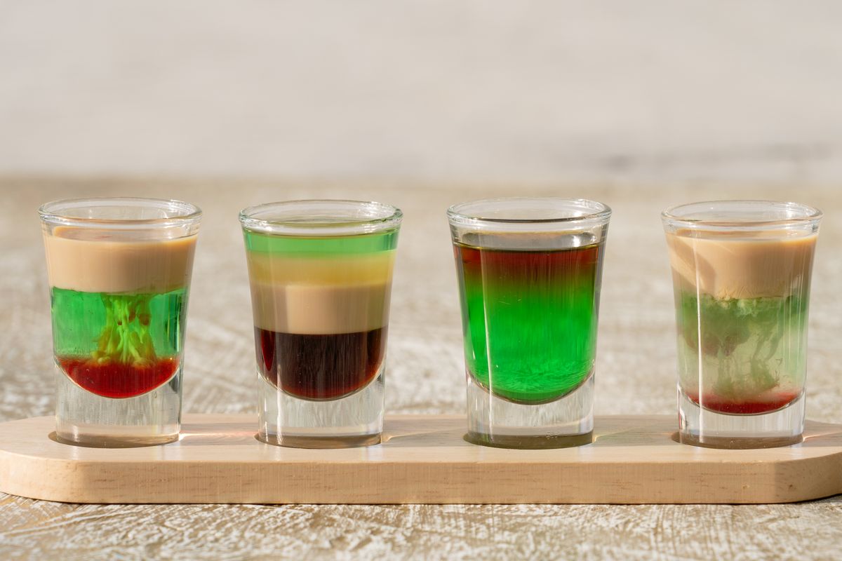 Vibrant green layered jello shots arranged on a wooden tray