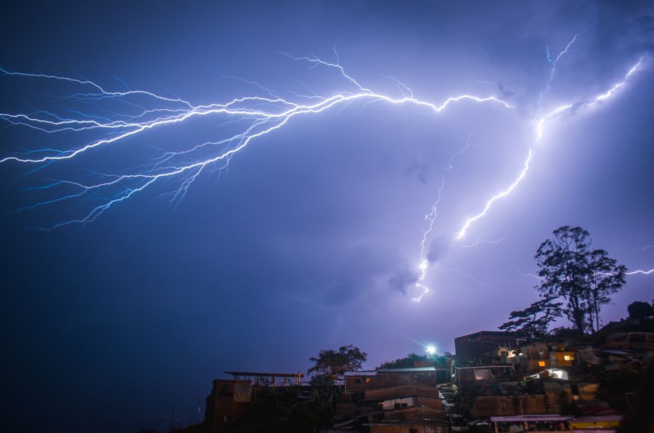 A striking thunderstorm with bright lightning above an urban setting at night.