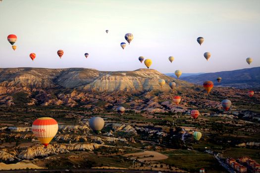A breathtaking aerial view of vibrant hot air balloons above Cappadocia's unique landscape at sunrise.