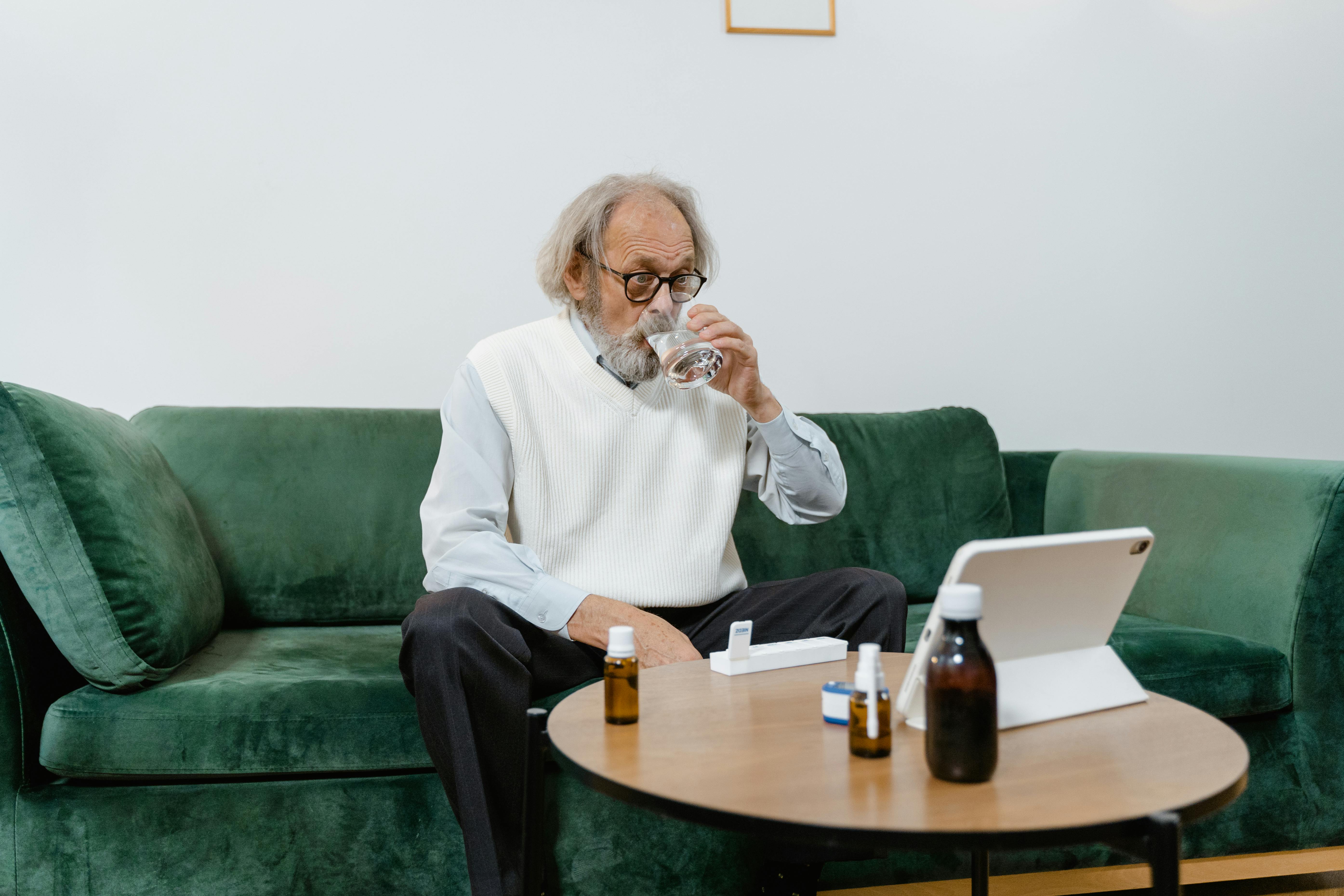 an elderly man drinking his medicines