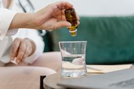 Person Holding Clear Drinking Glass With Brown Liquid
