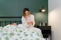 Woman in White Long Sleeve Shirt Sitting on Bed