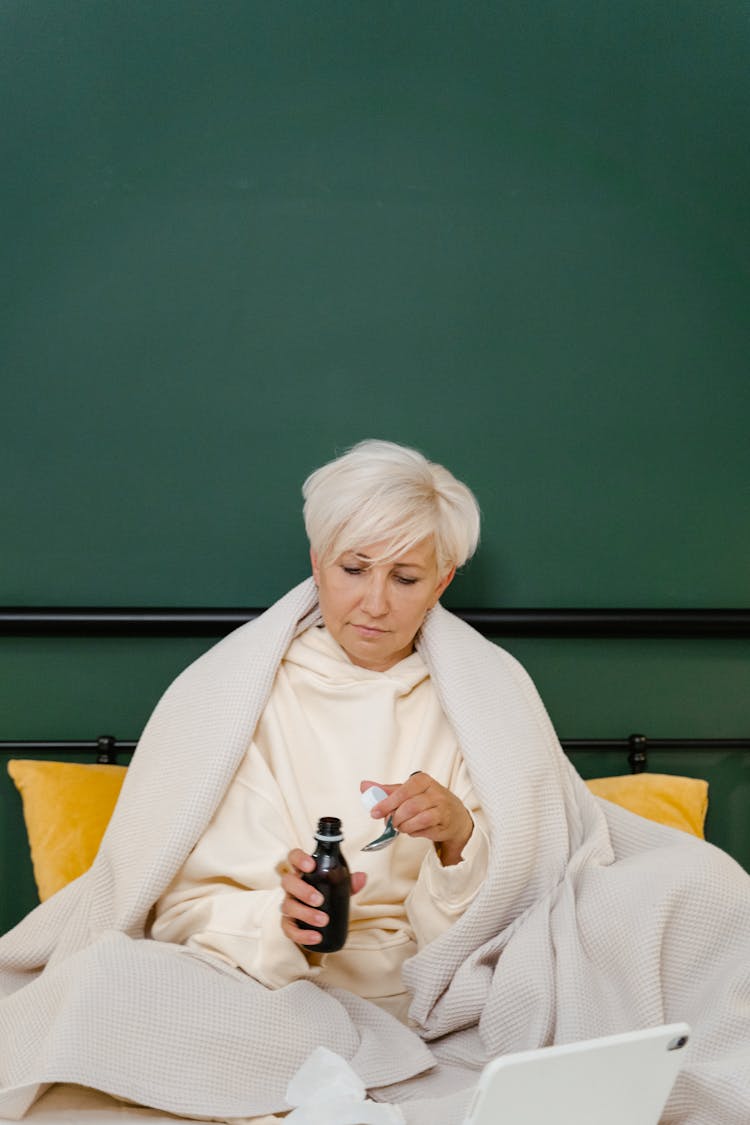 Woman Taking Her Medicine On The Bed