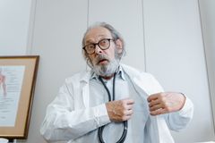 Surprised elderly doctor wearing lab coat and stethoscope indoors.