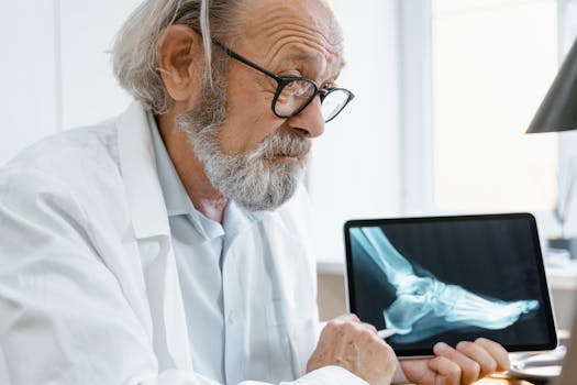 Elderly doctor in a white coat discussing X-ray results on a tablet during a video consultation.