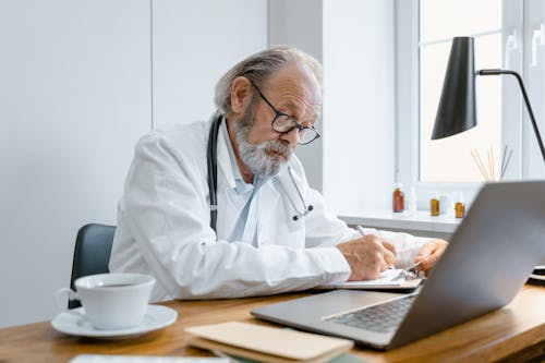 Free An Elderly Doctor Writing Prescription Stock Photo