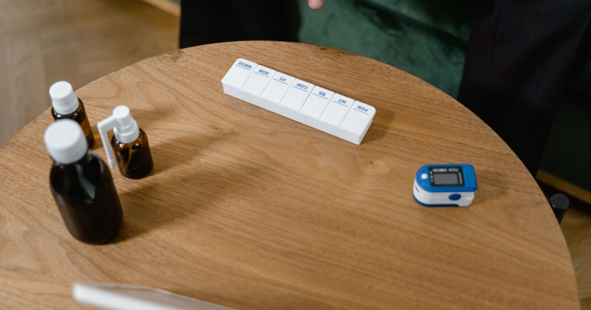 A weekly pill organizer and medication bottles arranged on a wooden table
