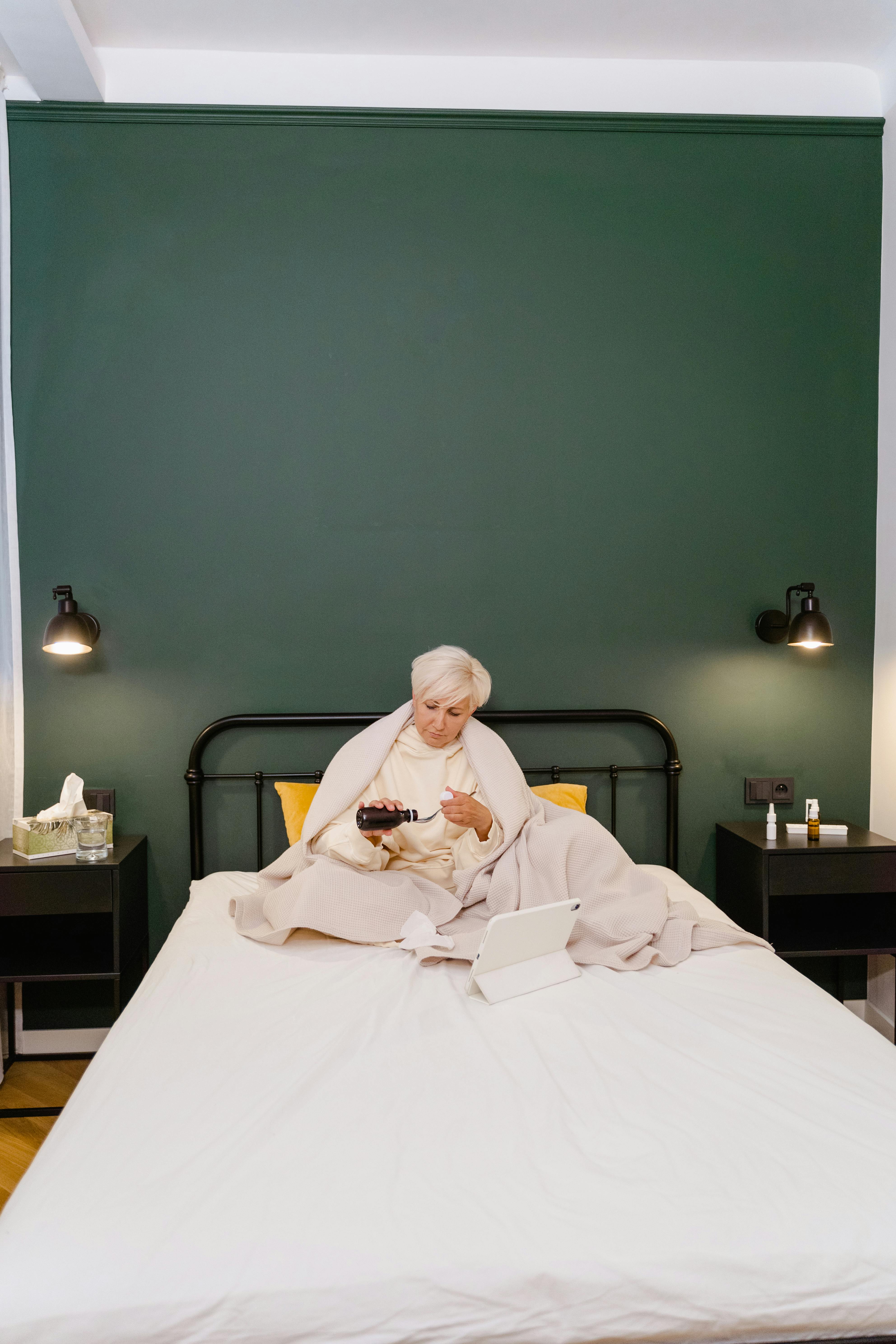 an elderly woman drinking her medicines in bed