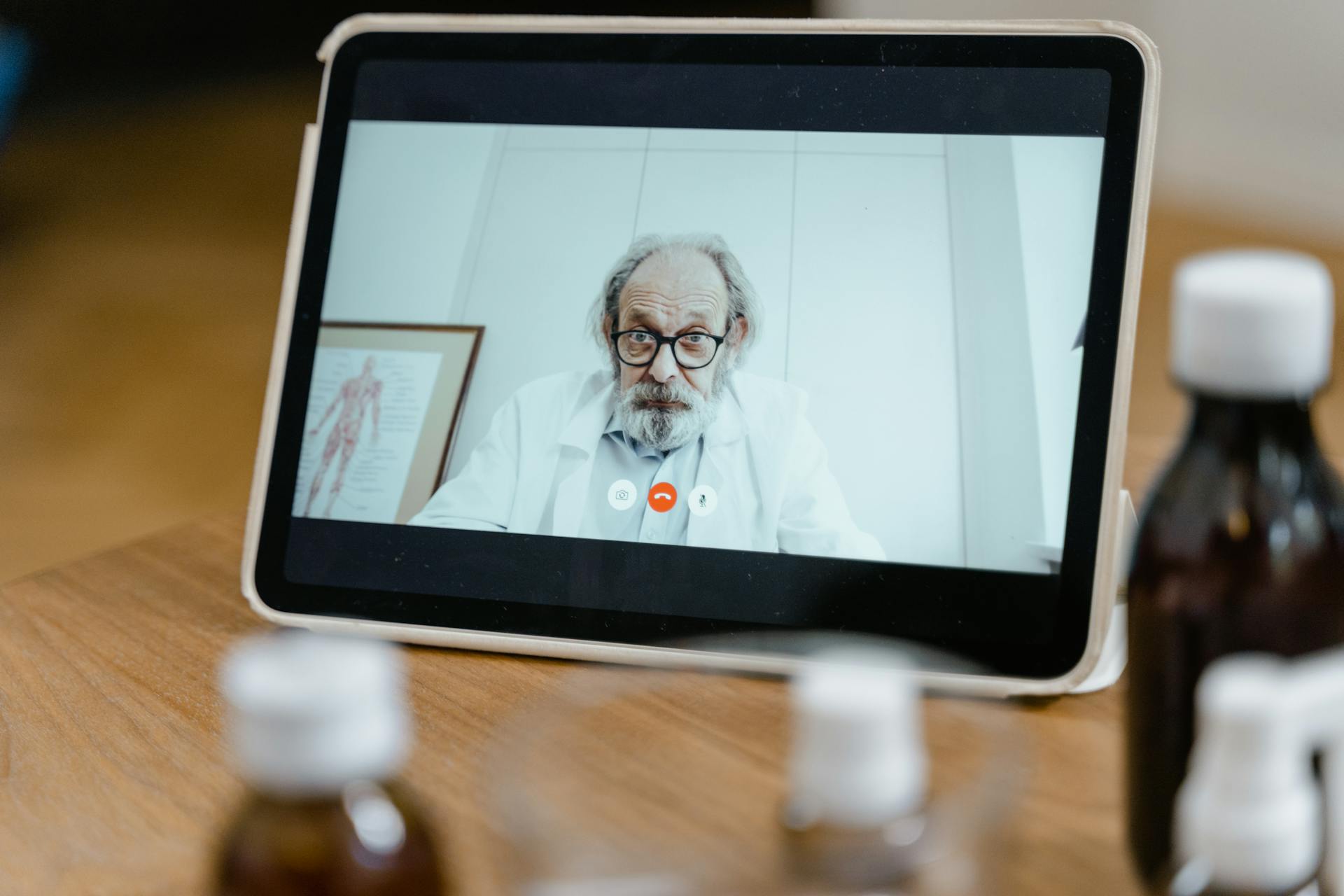 Elderly male doctor in white coat on a digital tablet screen during a virtual medical consultation.