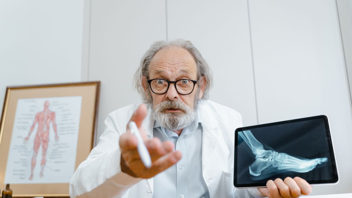 Senior doctor showing patient's X-ray on a tablet during telehealth consultation.