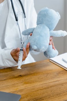 Healthcare professional demonstrates injection on teddy bear, symbolizing pediatric care.