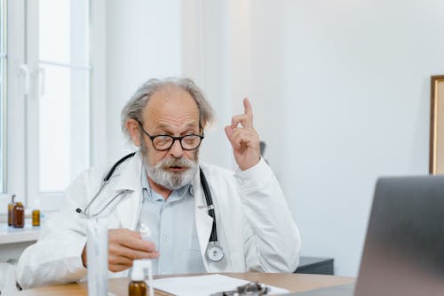 Free An Elderly Doctor Giving Online Consultation Stock Photo