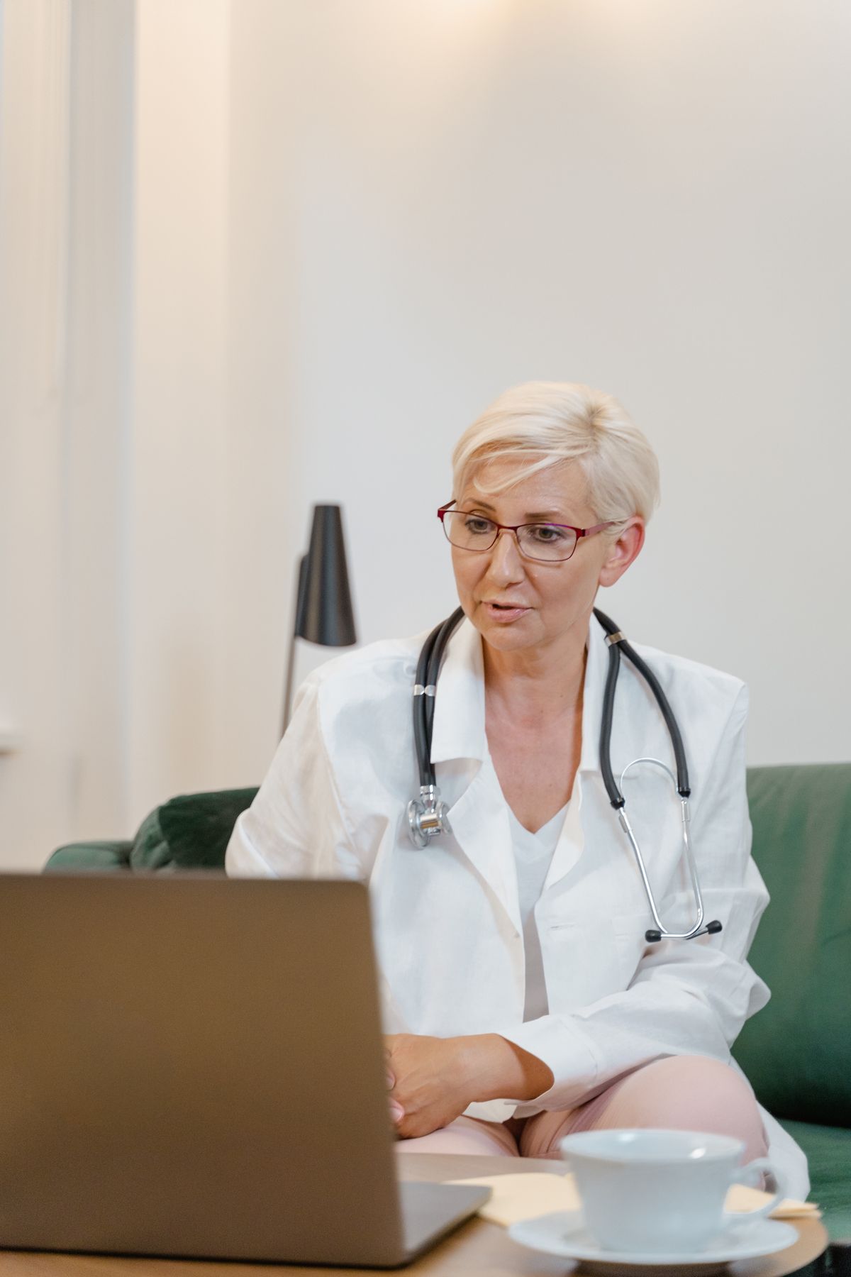 A senior doctor in a white coat speaking on a video call
