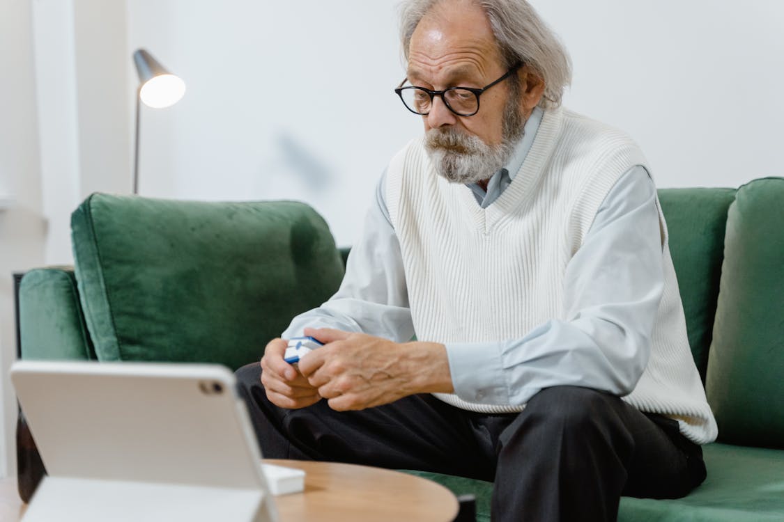Free An Elderly Man Sitting in a Couch Holding a Pulse Oximeter Stock Photo